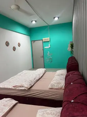 a room with two beds and a green wall at The Suncity Inn in Kampar