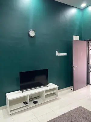 a living room with a tv and a clock on a wall at Nafisa Homestay in Kepala Batas