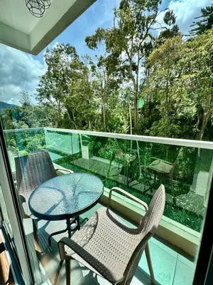 a balcony with a table and chairs and a view of trees at Ayaan Bliss Homestay at QuintetTanahRata in Cameron Highlands