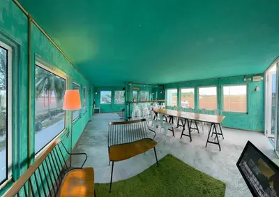a green room with a table and chairs and windows at PadiBox Homestay in Sekincan