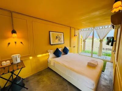 a yellow bedroom with a bed and a window at PadiBox Homestay in Sekincan