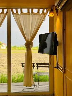 a window with a curtain and a tv on a porch at PadiBox Homestay in Sekincan