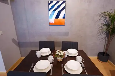 a dining room table with chairs and white dishes on it at Mahkota Valley Suites Kuantan by Iconique in Gua Sai