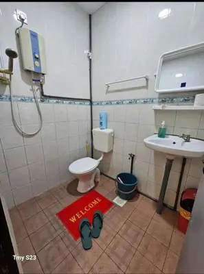 a bathroom with a toilet and a sink and a red welcome mat at Tasek Cermin Roomstay in Ipoh