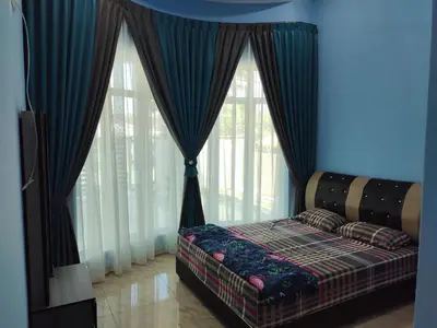a bedroom with a bed in front of windows at SUN HOMESTAY Teluk Intan