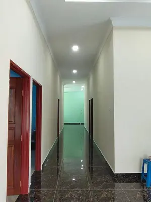 an empty hallway with white walls and tile floors at SUN HOMESTAY Teluk Intan