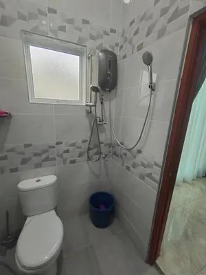 a bathroom with a shower with a toilet and a window at SUN HOMESTAY Teluk Intan