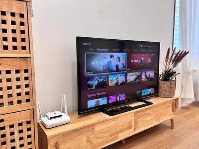 a flat screen tv sitting on top of a wooden stand at Corner Single-Storey Fire Camp 9pax FreeWiFi Ipoh Town By LUX SUITES in Ipoh