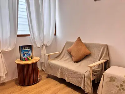 a room with a chair with a pillow and a table at Corner Single-Storey Fire Camp 9pax FreeWiFi Ipoh Town By LUX SUITES in Ipoh