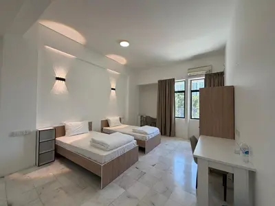 a hotel room with two beds and a desk at Stallions Suite Penang in Jelutong