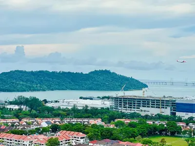an airplane flying over a city with a body of water at Luxury 2BR Rooftop Infinity Pool 8 Pax airport usm in Bayan Lepas