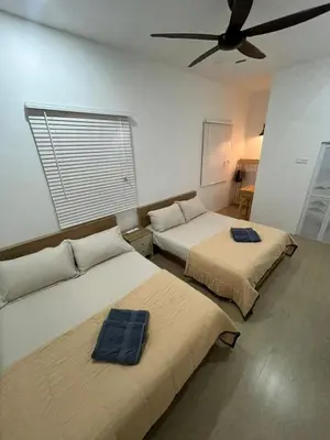 two beds in a room with a ceiling fan at Desa Ibol Cottage and River - Max 10Pax