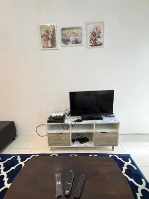 a living room with a table with a television and remote controls at AYAAN RAFFLESIA Home at Cameron Highland in Tanah Rata