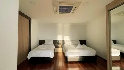 a bedroom with two beds with white sheets and a mirror at Sunrise Gurney Georgetwon in George Town