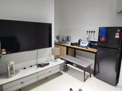 a living room with a desk and a large screen tv at Horizon Rooftop Skypool Condotel - Ipoh in Ipoh