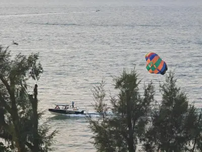 a kite flying over a boat in the water at By The Sea Fully Seaview all rooms Beach front in Batu Ferringhi