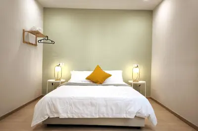 a bedroom with a bed with a yellow pillow and two lamps at Taiping town area - 3 bedroom in Taiping