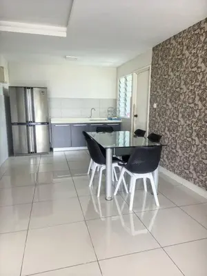 a kitchen with a table and chairs and a refrigerator at Rainbow Apartment by Renuka in Butterworth