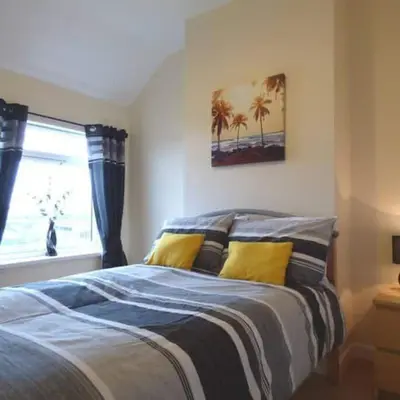 a bedroom with a bed with yellow pillows and a window at Rainbow Apartment by Renuka in Butterworth