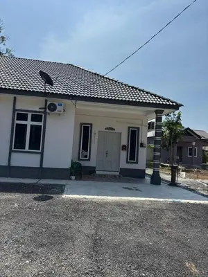a small white house with a driveway at Airisafiq Homestay in Kampong Sungai Rambai