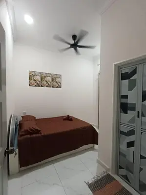 a bedroom with a bed and a ceiling fan at Airisafiq Homestay in Kampong Sungai Rambai
