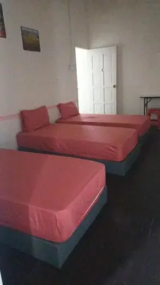 two beds in a room with red sheets at Affordable Nice and Comfortable Room in George Town
