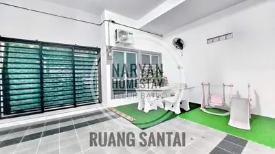 a living room with a table and green carpet at Naryan Homestay Teluk Batik in Lumut