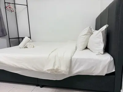 a bed with white sheets and pillows in a room at Austin Taman Daya Large Corner House for 10 Pax in Gua Sai