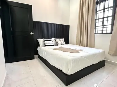 a bedroom with a large bed with a black headboard at Spacious Classic 4BR Family Haven I Simpang Ampat in Simpang Ampat