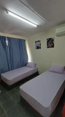 two beds in a room with blue curtains at POLI Homes in George Town