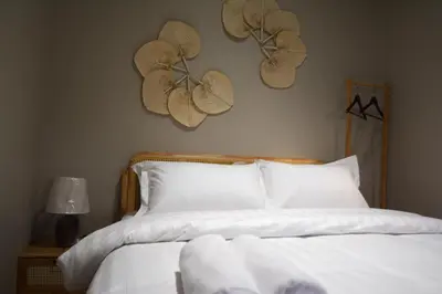 a bed with white sheets and hats on the wall at Morikoi Cottage in Ipoh