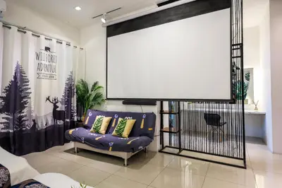 a large screen in a living room with a couch at 32 cozy stay Projector, Karaoke , BBQ, 7 carpark in Ipoh