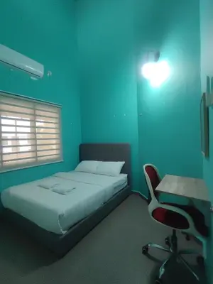a bedroom with a bed and a desk and a chair at Cozy Corner Homestay Bandar Utama Gua Musang in Gua Musang