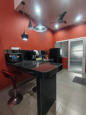 a kitchen with a black counter and red walls at Cozy Corner Homestay Bandar Utama Gua Musang in Gua Musang
