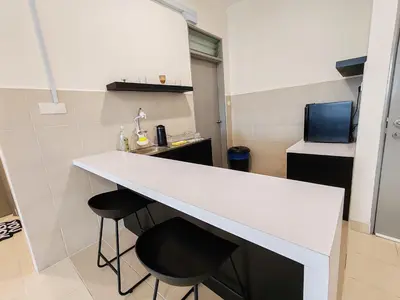 a kitchen with a white counter and two stools at BW Urban Stay in Ipoh