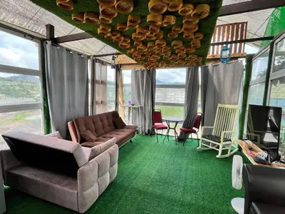 a living room with a couch and a table and windows at Mountain View Sameer Glamping in Cameron Highlands