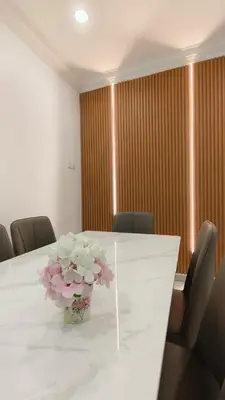 a white table with a vase of flowers on it at DouDou's House in Simpang Ampat