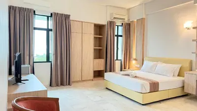 a bedroom with a bed and a desk and a television at Stallions Suite Penang in Jelutong