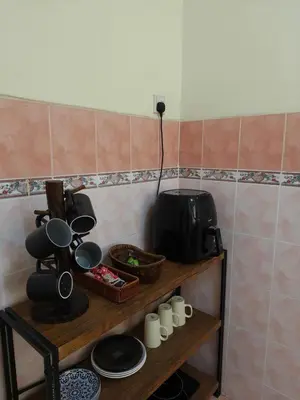 a kitchen with a shelf with dishes and a microwave at Tambun Apartment - Boho Natura in Tambun