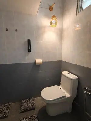 a bathroom with a white toilet and a light at Tambun Apartment - Boho Natura in Tambun
