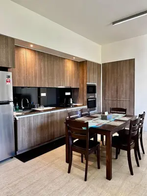 a kitchen with a table and chairs and a refrigerator at By The Sea partial seaview 2BR 6pax Batu Ferringhi in Batu Ferringhi