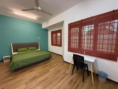 a bedroom with a bed and a desk and two windows at Green Living Homestay Bercham 8 Pax in Ipoh