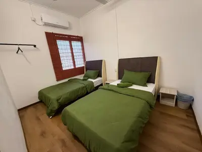 two beds in a room with green and white at Green Living Homestay Bercham 8 Pax in Ipoh