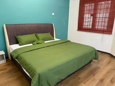 a bedroom with a bed with a green blanket at Green Living Homestay Bercham 8 Pax in Ipoh