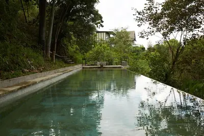 a pool of green water with a house in the background at Mountain View Getaway House with Pool Lauhaus 1 in Kuala Kubu Baharu