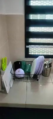 a kitchen counter with a shelf with dishes and a window at Homestay odah dan hana teluk intan 3R2T in Teluk Intan