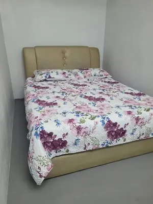 a bed with a floral comforter on top of it at BUDI HOMESTAY Meru Jaya in Ipoh