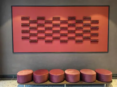 a row of pink stools in front of a painting at The Stallionz Classy Suites by LH - Ipoh Town in Ipoh