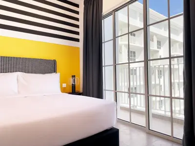 a bedroom with a white bed and a large window at Stallionz by KLIQ in Ipoh