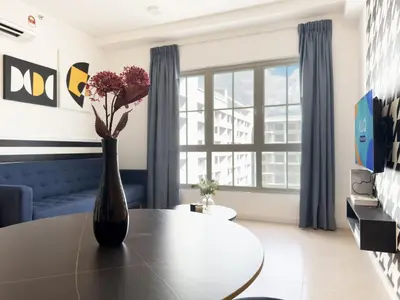 a living room with a table and a vase with flowers at Stallionz by KLIQ in Ipoh